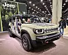 Jeep Recon SUV with doors removed on display at an indoor auto show stand.