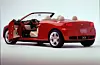 Red Ford Libré concept car with open doors, cream seats and a low, sculpted body on a plain studio background.